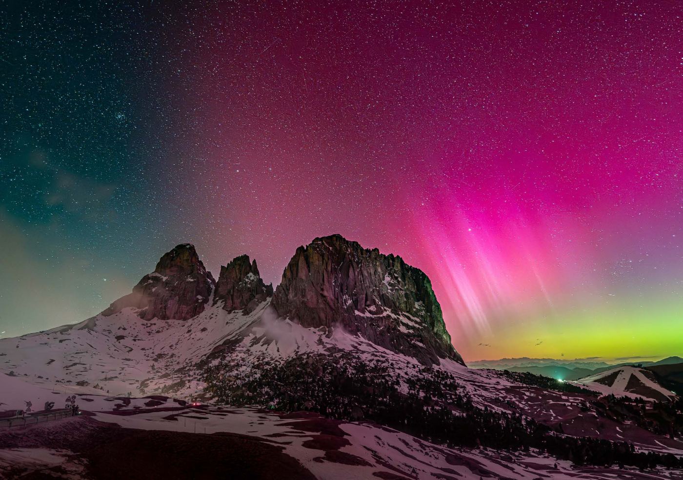 Aurora boreale rosa e verde sopra le cime dolomitiche