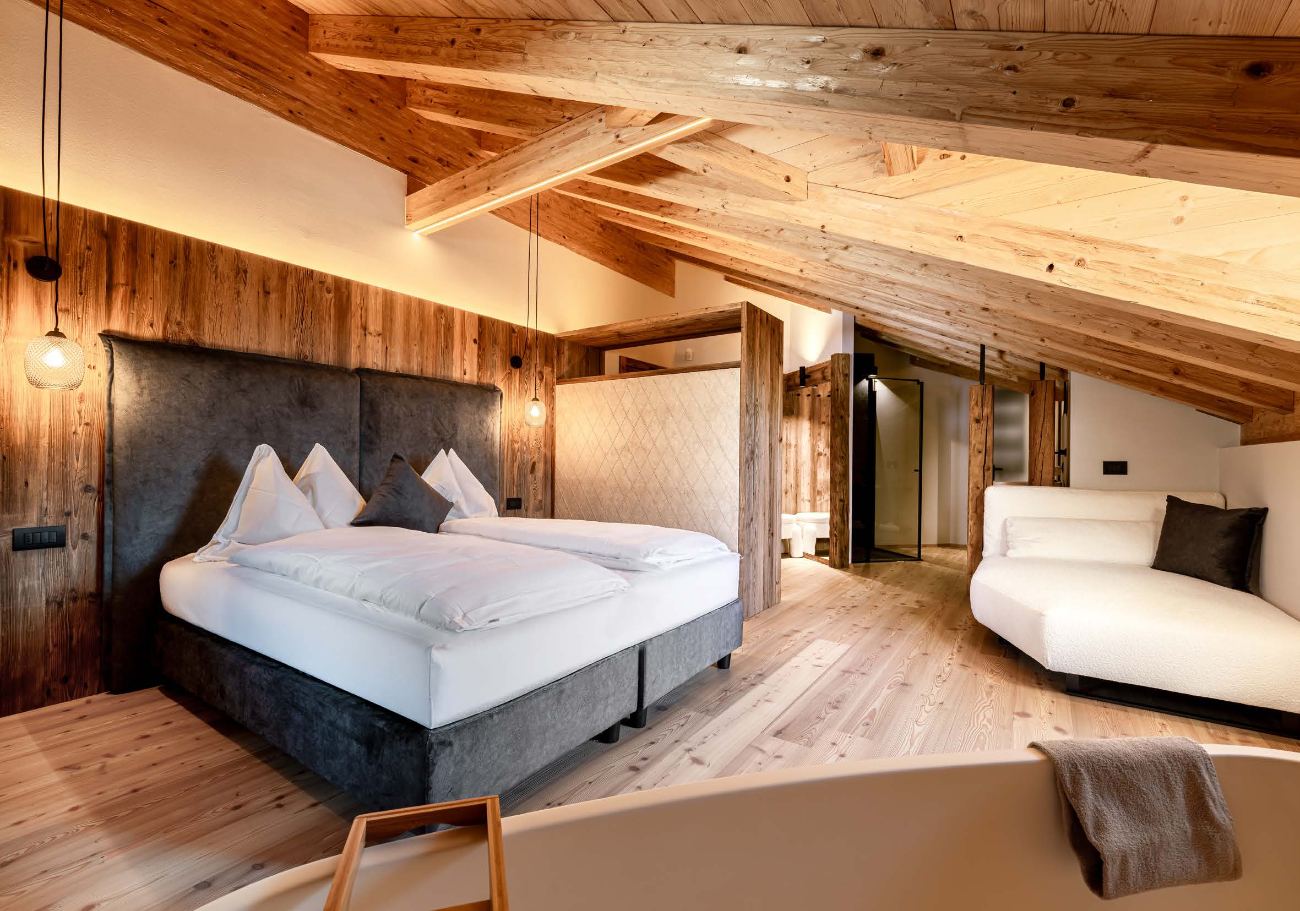 Camera mansardata con letto e travi in legno a vista