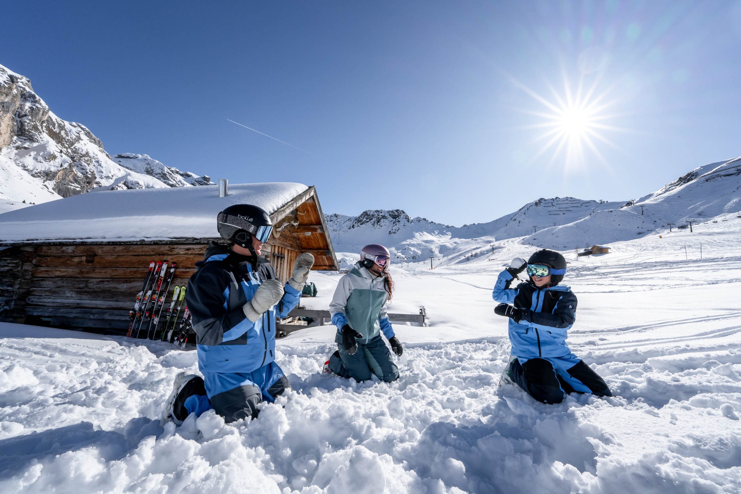 Bambini giocano nella neve davanti a una baita di legno
