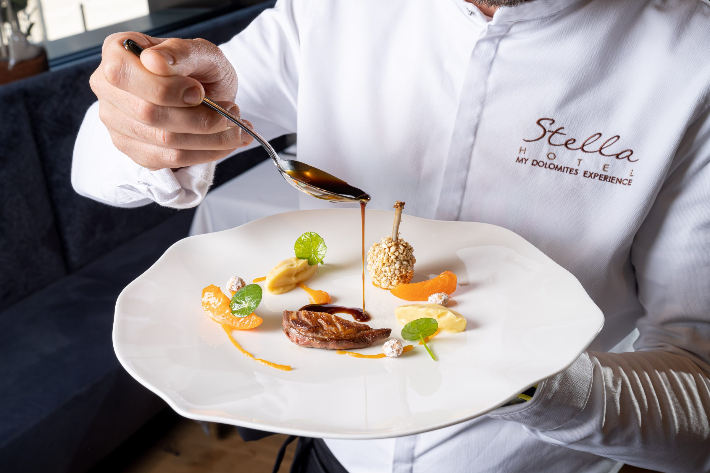 Chef versa la salsa per completare un piatto gourmet