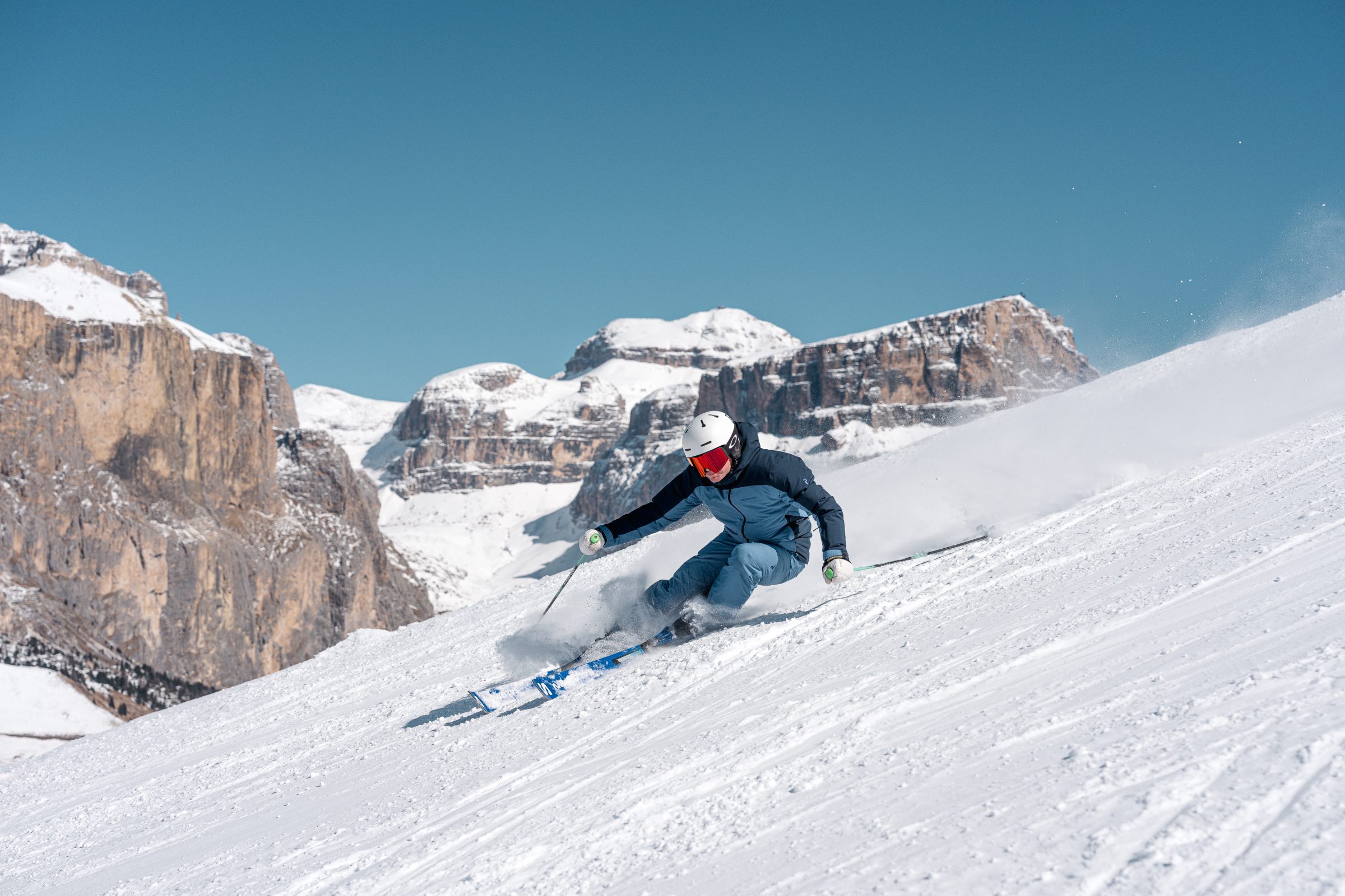 Sciatore in discesa con il gruppo del Sella sullo sfondo