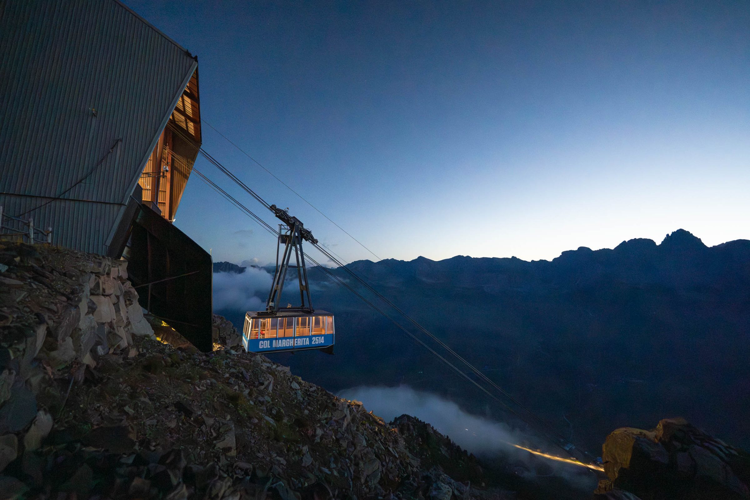 Cabina di una funivia all'alba con le vallate sotto le nuvole