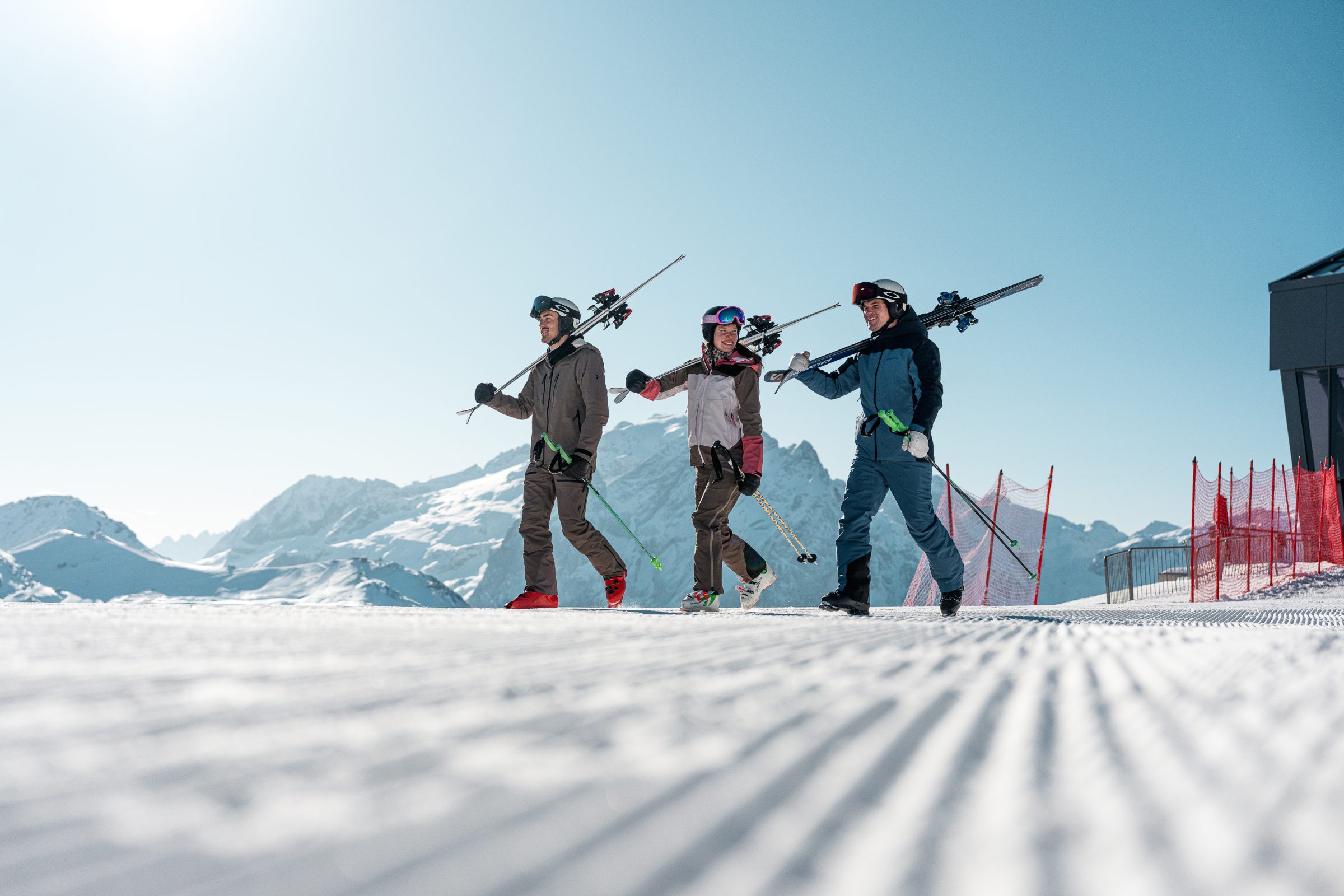 Tre scialpinisti salgono con gli sci in spalla lungo la pista