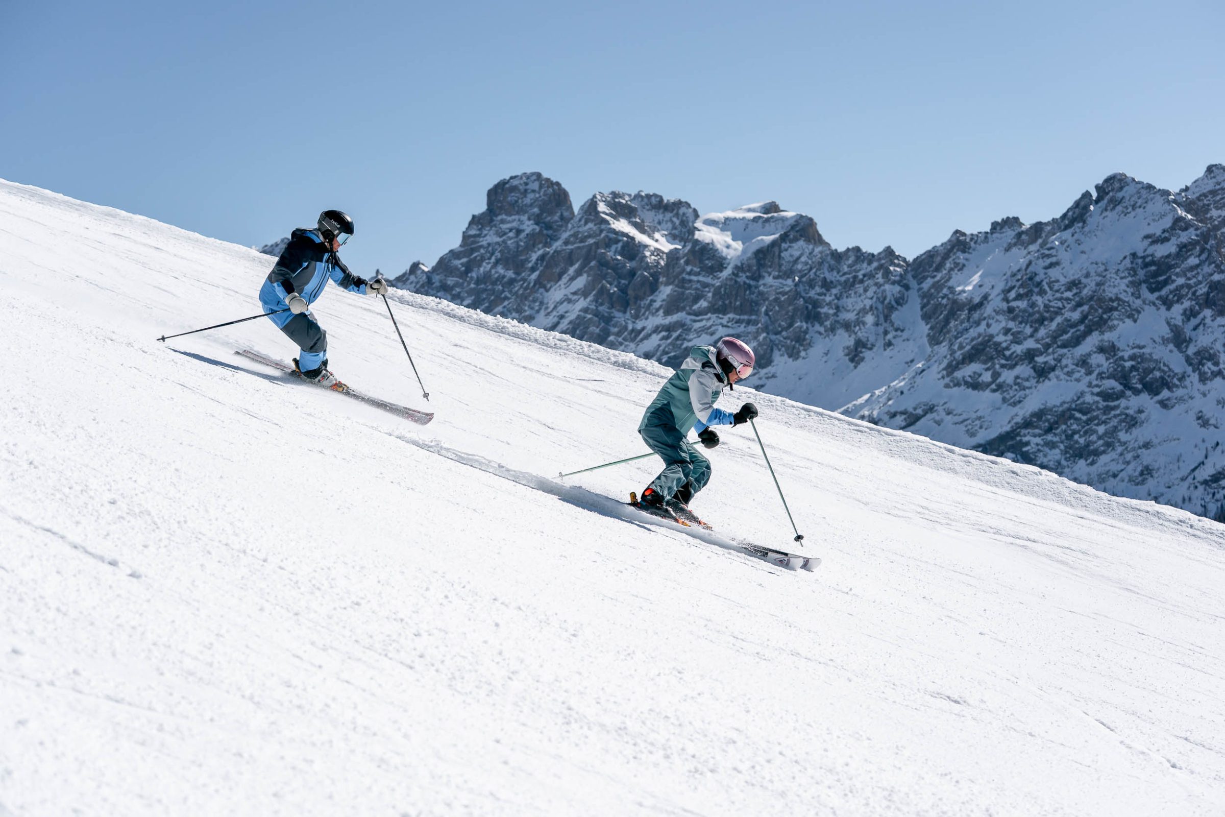 Sciatore in discesa con le cime innevate sullo sfondo