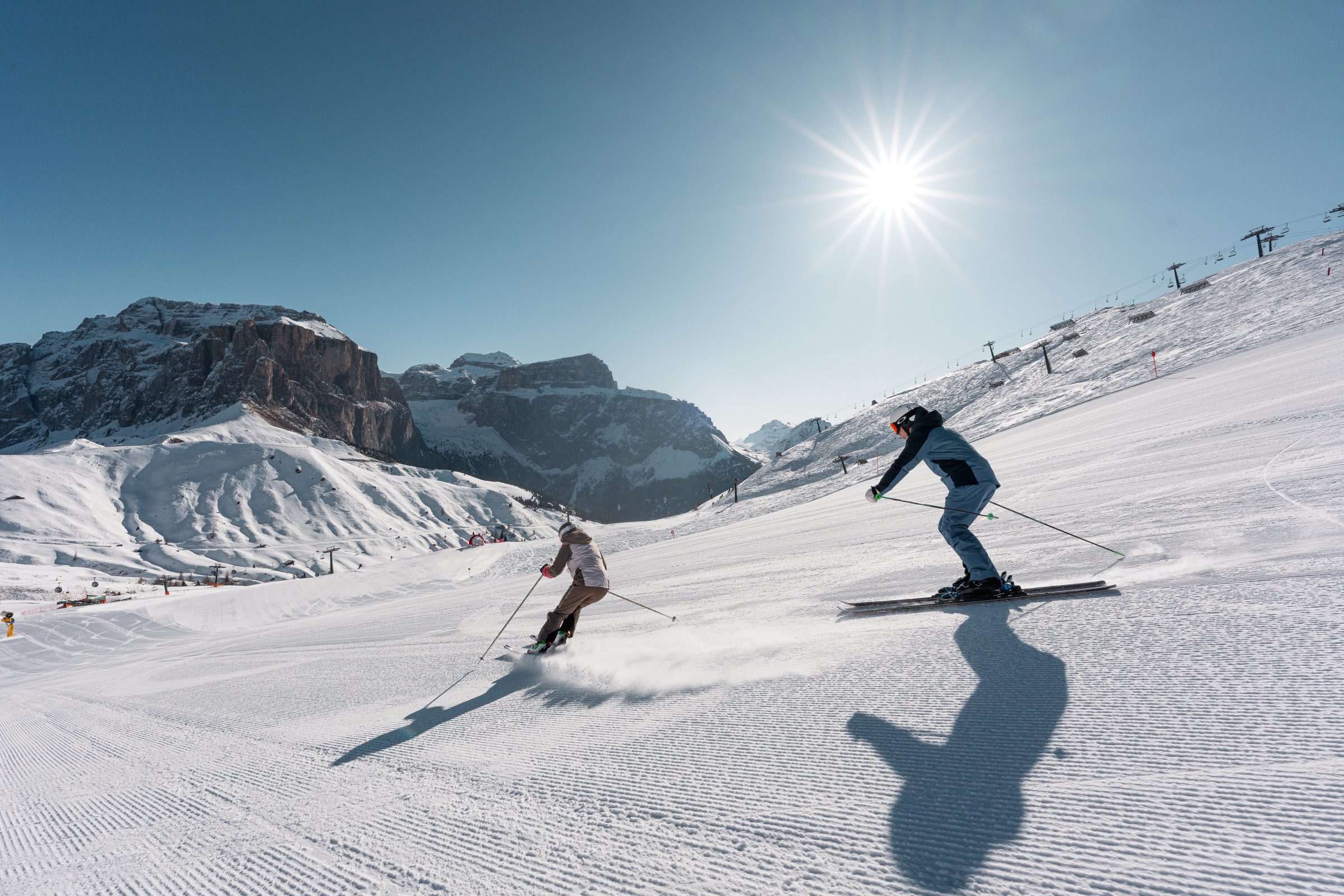 Sciatore in discesa controluce con la lunga ombra sulla neve
