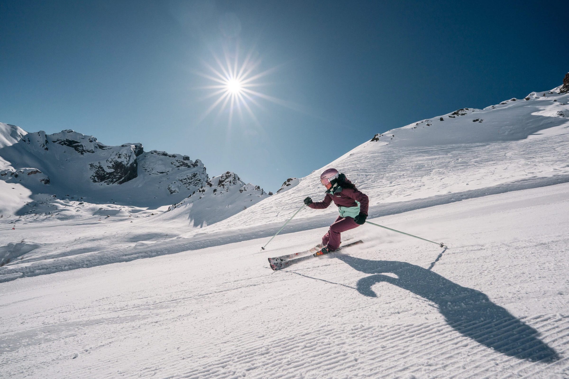 Sciatore in discesa con il sole basso sopra la pista